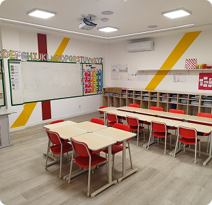 Sala de aula com carteiras vermelhas e decoração amarela e vermelha na parede