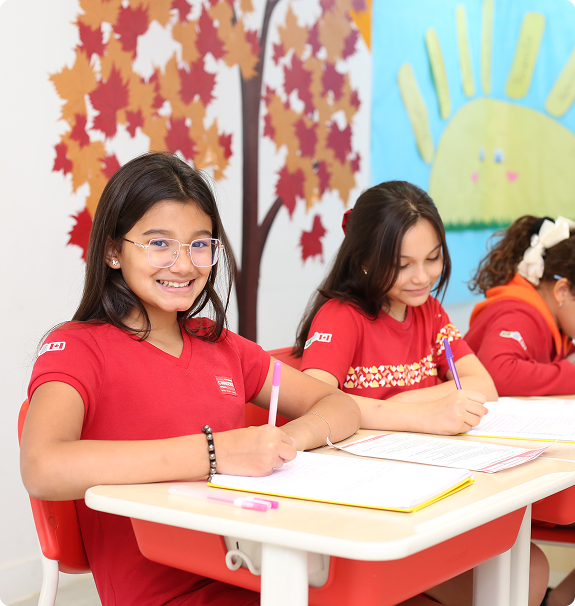 Três alunas escrevendo em mesa escolar da Escola Canadense de Belém